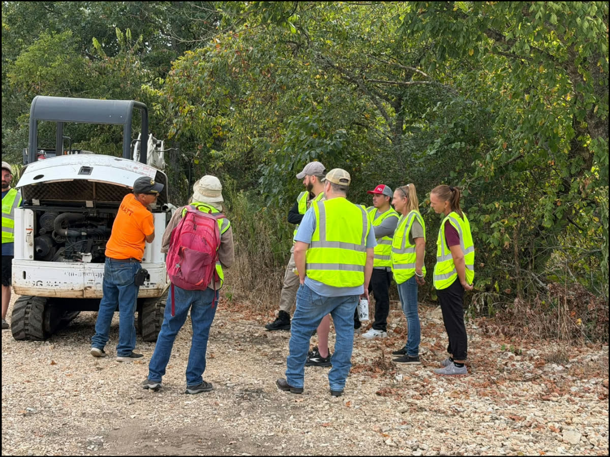 ACDC students gathered around a skid steer for a hands-on walkaround lesson